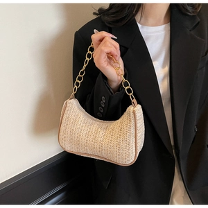 Detail of woven straw hobo bag with gold chain strap and brown leather trim accents
