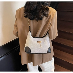 Détail du sac sous le bras en toile avec pendentif cerf doré et bandoulière en cuir et chaîne