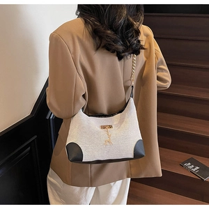 Détail du sac bandoulière en toile et cuir avec pendentif élan doré et bandoulière