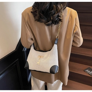 Détail du sac bandoulière en toile avec breloque cerf dorée et bandoulière en chaîne