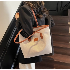Detail of large canvas tote bag with brown leather handles and straps in a lifestyle shot