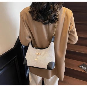 Détail du sac bandoulière rétro en tissu crème avec bordure noire et chaîne dorée