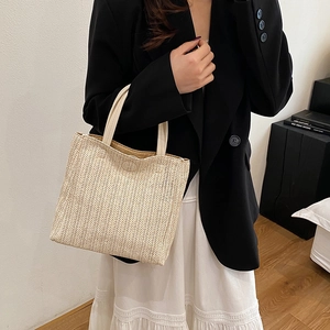 Minimalist woven straw handbag in cream white with PU handles shown with a fashion model
