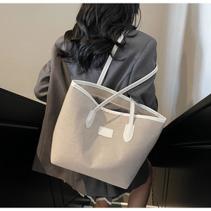 Rear view of a model wearing the large canvas tote bag with white leather trim details