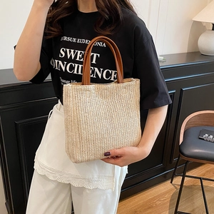 Handmade woven straw tote bag with brown leather handles and herringbone pattern