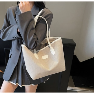 Close-up of a spacious canvas tote bag in beige with white trim and double shoulder straps