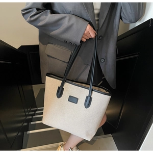 Close-up of minimalist large woven tote bag with black leather trim and handles