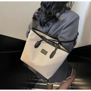 Detail view of a minimalist large canvas tote bag with black leather straps and trim