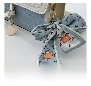 Detail of blue leather bag with elegant bow scarf and gold pendant accessory