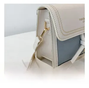 Detail of high-quality gold-tone metal hook and stitching on stylish mini square bag