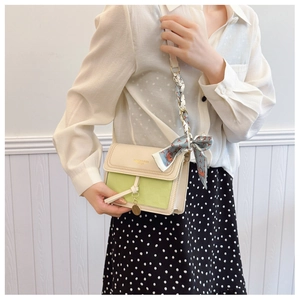 Detail of lime green and off-white shoulder bag with floral scarf and metal pendant