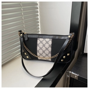 Macro detail of black vintage baguette bag with gold chain and floral pattern