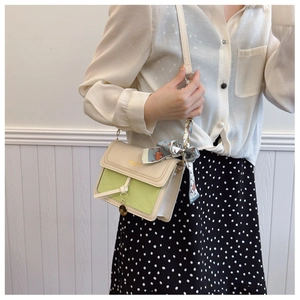Detail of cream and green crossbody bag with silk scarf and gold metal logo charm
