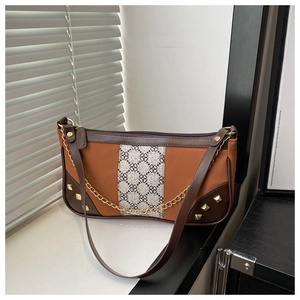 Detail of crossbody bag featuring brown patchwork, gold studs, and elegant chain strap