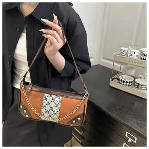Detailed close-up of brown leather bag with orange paneling and decorative gold chain