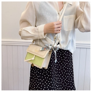 Detail of color-block crossbody bag with lychee texture and silk scarf accessory