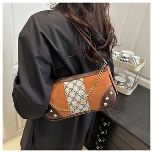 Detail of vintage patchwork bag featuring orange leather and gold metal chain strap