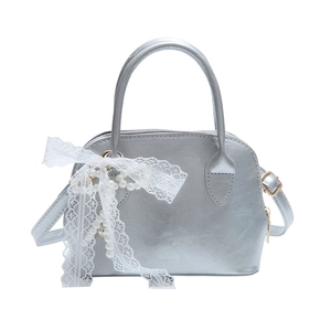 Silver shell-shaped leather handbag with lace bow and pearl pendant on white background