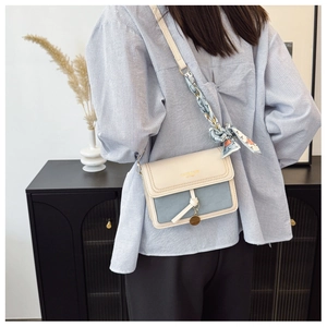 Detail view of two-tone crossbody bag with elegant floral silk scarf wrapped on handle
