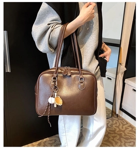 Detail view of coffee brown leather Boston bag with trendy baseball themed charms