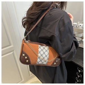 Detail of color-block crossbody bag with gold chain and square rivet accents