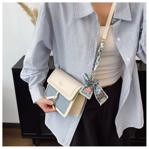Detail of blue cream crossbody bag with floral silk scarf and gold heart charm