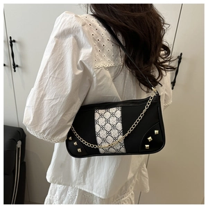 Detailed close-up of a vintage black and white contrast baguette bag with gold chain strap