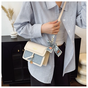 Detail of a light blue checkered crossbody bag with silk scarf and gold metal hardware
