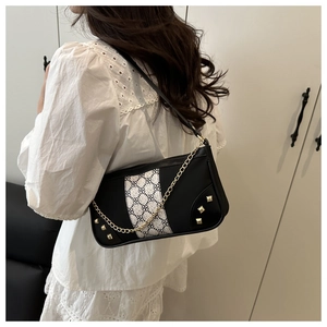 Close-up of black underarm bag featuring argyle print, gold studs and chain detail