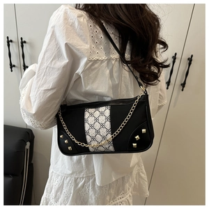 Detail of black retro shoulder bag with white diamond pattern and gold chain on model
