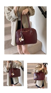 Detail of burgundy leather handbag featuring a creative baseball charm and silver hardware