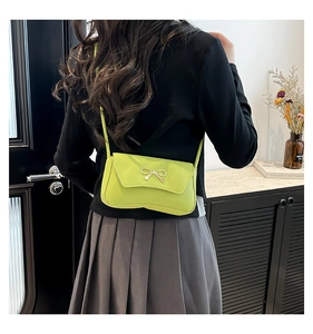 Gros plan d'un sac à bandoulière vert clair avec boucle nœud doré en cuir lisse et souple