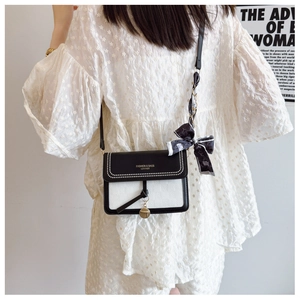 Detailed view of bicolor crossbody bag with metal stud trim and decorative printed silk scarf
