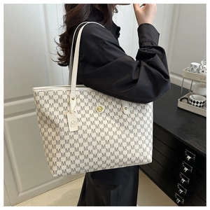 Detail view of large cream tote bag featuring M-letter print and gold logo hardware