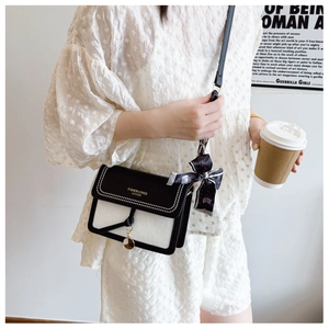 Detail of cream square crossbody bag with silk scarf accent and gold lettering