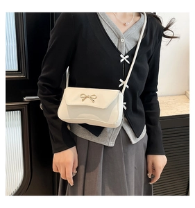 Détail du sac à bandoulière blanc en similicuir avec ornement nœud doré métallique