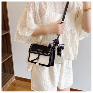 Detail view of the black and white crossbody bag with gold lettering and decorative silk scarf