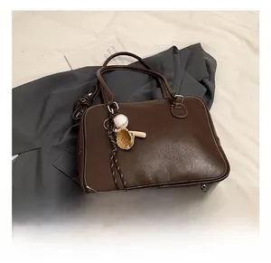 Close-up of vintage dark brown tote bag with white contrast stitching and baseball charm
