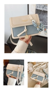 Detail of cream square bag with lychee grain leather, silk scarf, and gold charm
