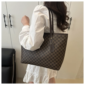 Detailed close-up of a large tote bag featuring brown M-patterned canvas and leather straps
