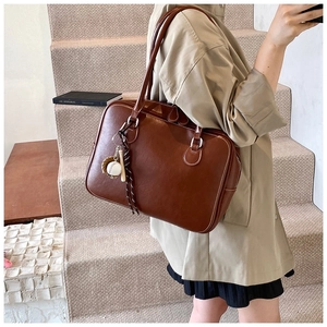 Detail of vintage brown tote bag in matte PU leather with baseball charm on a model