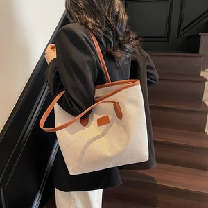 Large beige canvas tote bag with brown leather trim shown in a stylish indoor setting