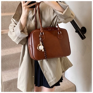 Vintage brown leather tote bag with creative baseball charm shown in commute styling