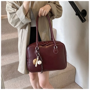 Macro shot of dark red vintage leather tote featuring baseball charm accessories