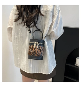 Detail of cylinder bucket bag featuring leopard print panel and black leather stitching