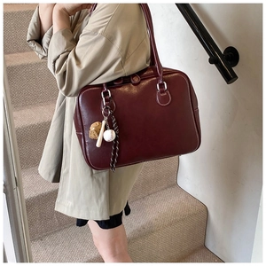 Detail of dark brown leather tote bag with silver hardware and baseball bag charm