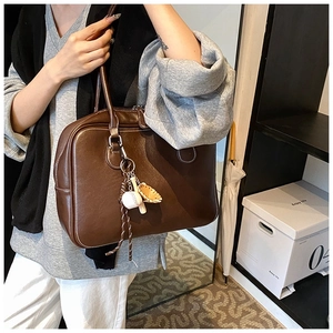 Detail view of large dark brown retro tote bag with white stitching and baseball charm