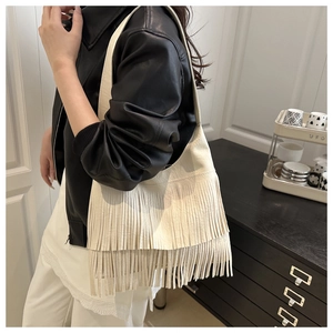 Détail du sac à bandoulière à franges blanc crème sur modèle pour un look décontracté