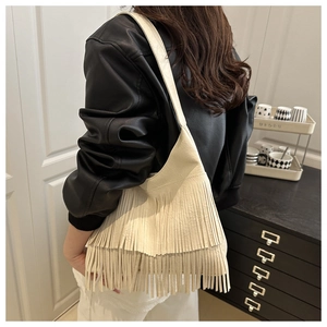Model wearing a cream bohemian fringe shoulder bag with long leather tassels