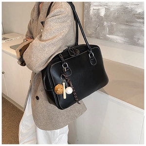 Chic black leather Boston bag worn with a beige blazer in a stylish interior setting